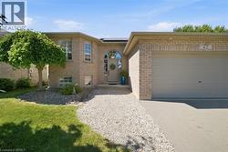 Brick exterior featuring an arched entryway, attached garage, and gravel pathway leading to the front door - 
