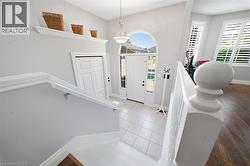 Foyer featuring a grand arched transom window above the front entry door, tile flooring, and a chandelier - 