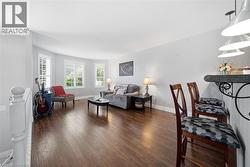 Spacious living area featuring wood-finish flooring, light gray wall tones, and white baseboards - 
