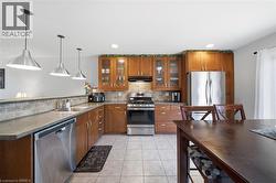 Kitchen featuring wood cabinetry, stainless steel appliances, tile backsplash, and ceramic tile flooring - 