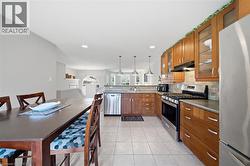 Kitchen featuring tile flooring, wood cabinetry, stainless steel appliances, and a tile backsplash - 
