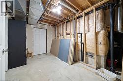 Unfinished basement space featuring exposed wooden ceiling joists, concrete flooring, and partial wall framing - 