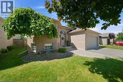 Light-colored brick exterior featuring an attached two-car garage, an arched entryway, and a mature weeping mulberry tree - 