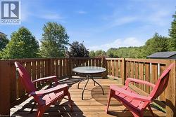 Wood-finish deck featuring a slatted wood railing, ample outdoor space, and surrounding mature trees - 