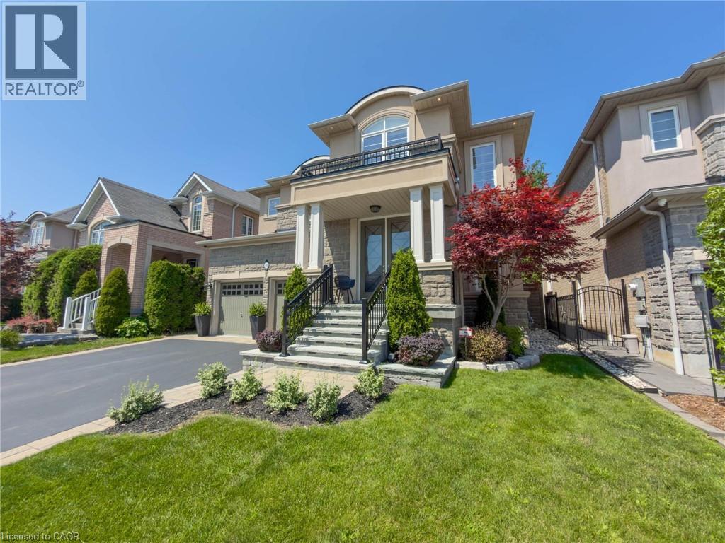 Stately facade featuring a stone and stucco exterior, prominent front porch with columns, wrought iron railings, and an integrated garage - 80 Sutherland Crescent, Ancaster, ON - Outdoor With Facade