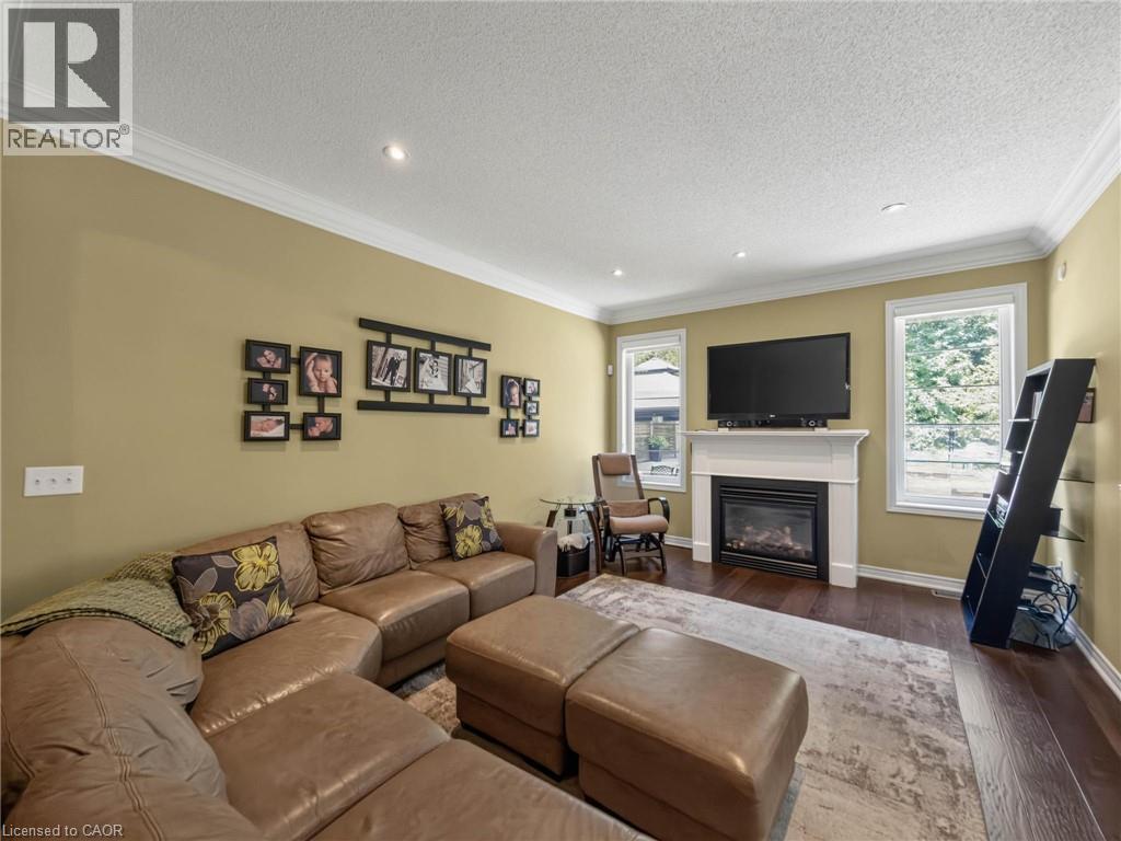 Living area featuring wood-finish flooring, recessed lighting, and crown molding - 80 Sutherland Crescent, Ancaster, ON - Indoor Photo Showing Living Room With Fireplace