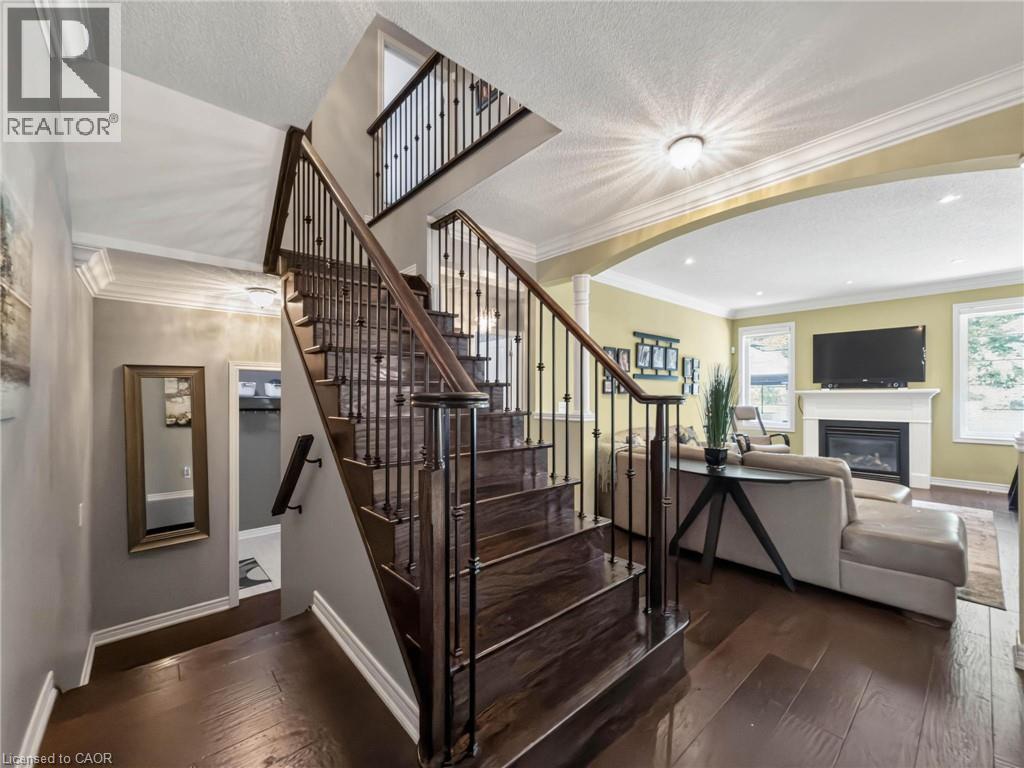 Dark wood-finish staircase with wrought iron balusters - 80 Sutherland Crescent, Ancaster, ON - Indoor Photo Showing Other Room With Fireplace