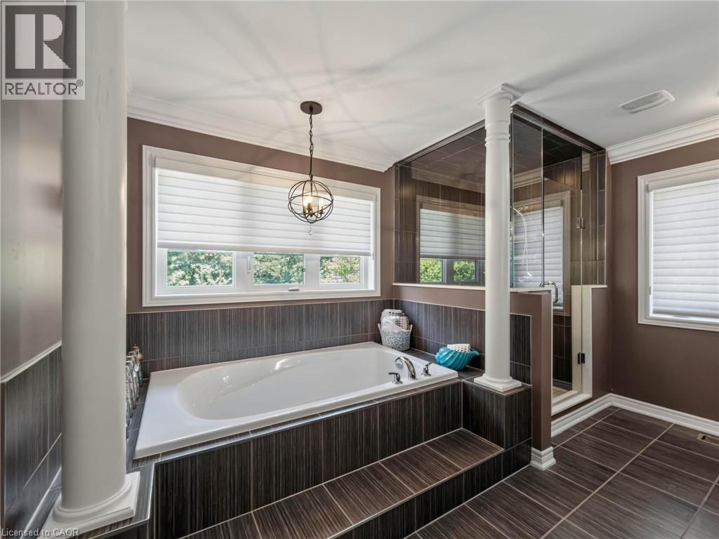 Built-in soaking tub with dark wood-finish tile surround, complemented by a glass-enclosed shower with vertical dark tile - 80 Sutherland Crescent, Ancaster, ON - Indoor Photo Showing Bathroom