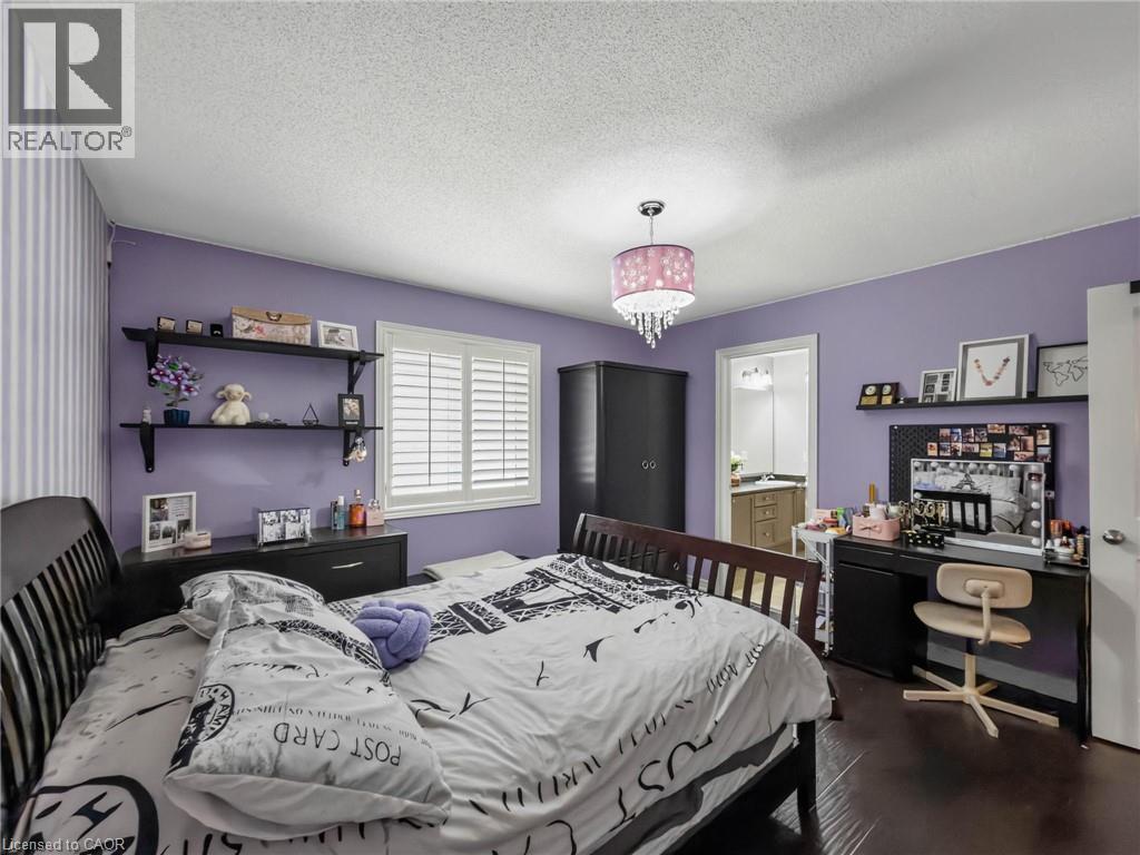 Spacious bedroom featuring lavender walls, dark wood-finish flooring, and abundant natural light from shuttered windows - 80 Sutherland Crescent, Ancaster, ON - Indoor Photo Showing Bedroom