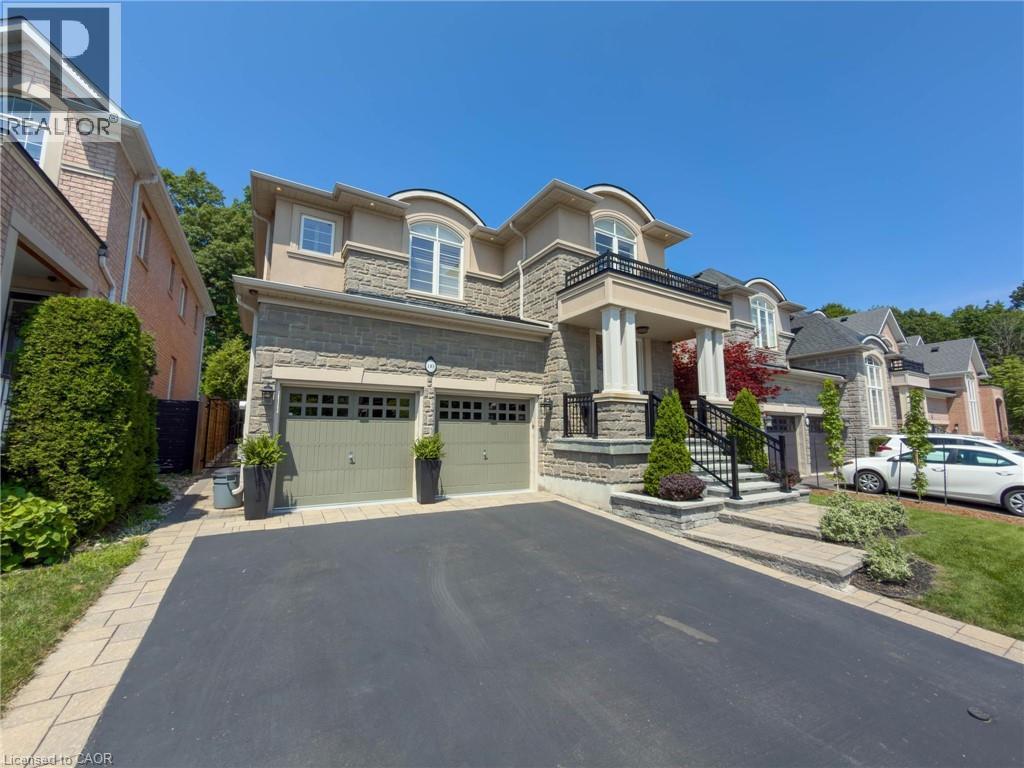 Two-story residence featuring a stone and stucco facade, a two-car garage, an arched portico with columns, and a paved driveway with paver edging - 80 Sutherland Crescent, Ancaster, ON - Outdoor With Facade