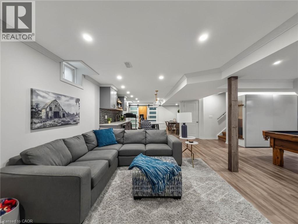 Lower-level living space featuring recessed lighting, crown molding, wood-finish flooring, and a kitchen area with a tiled backsplash - 80 Sutherland Crescent, Ancaster, ON - Indoor Photo Showing Living Room
