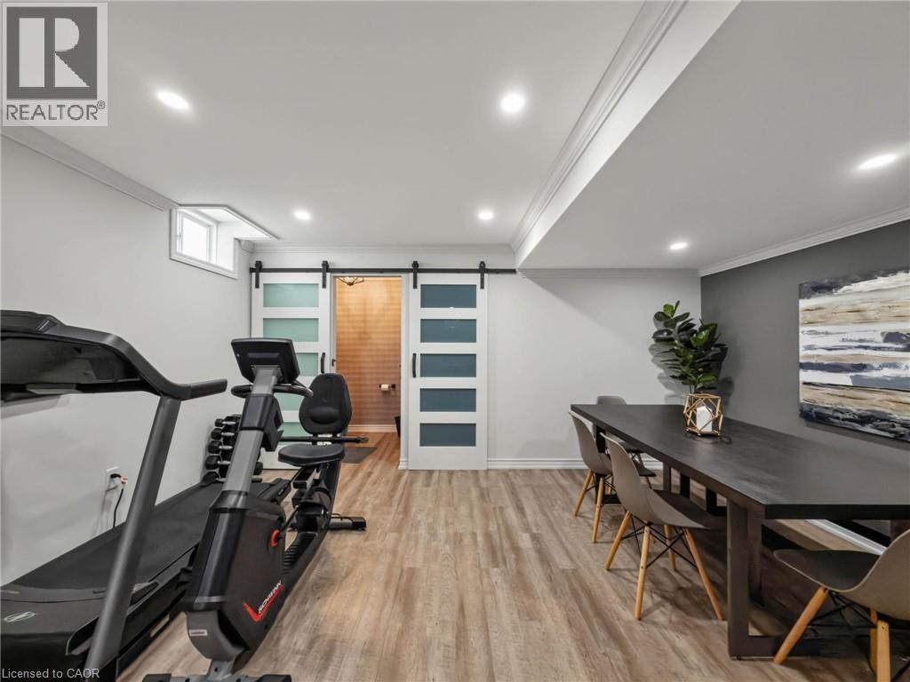 Spacious multi-purpose room featuring recessed lighting, crown molding, and wood-finish flooring - 80 Sutherland Crescent, Ancaster, ON - Indoor Photo Showing Gym Room