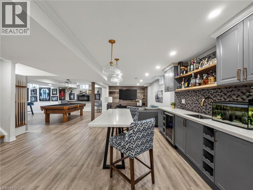 Open-concept living space featuring a modern kitchen with gray cabinetry, white quartz countertops, and a patterned tile backsplash, paired with a wood-finish island and seating for multiple guests - 80 Sutherland Crescent, Ancaster, ON - Indoor Photo Showing Other Room