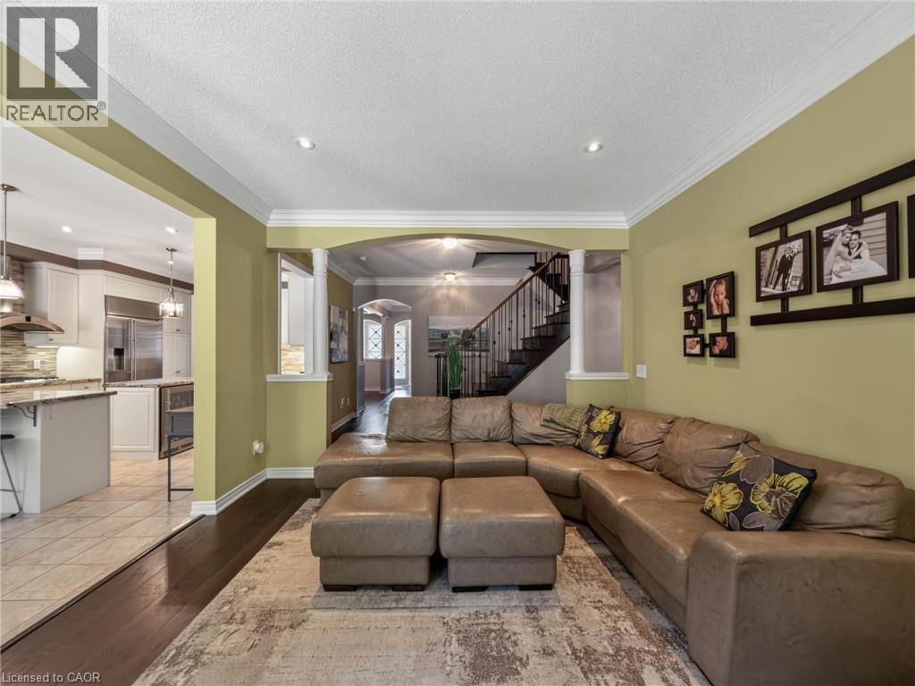 Spacious family room showcasing a tan leather sectional with coordinating ottomans, neutral area rug, and recessed ceiling lighting - 80 Sutherland Crescent, Ancaster, ON - Indoor Photo Showing Living Room