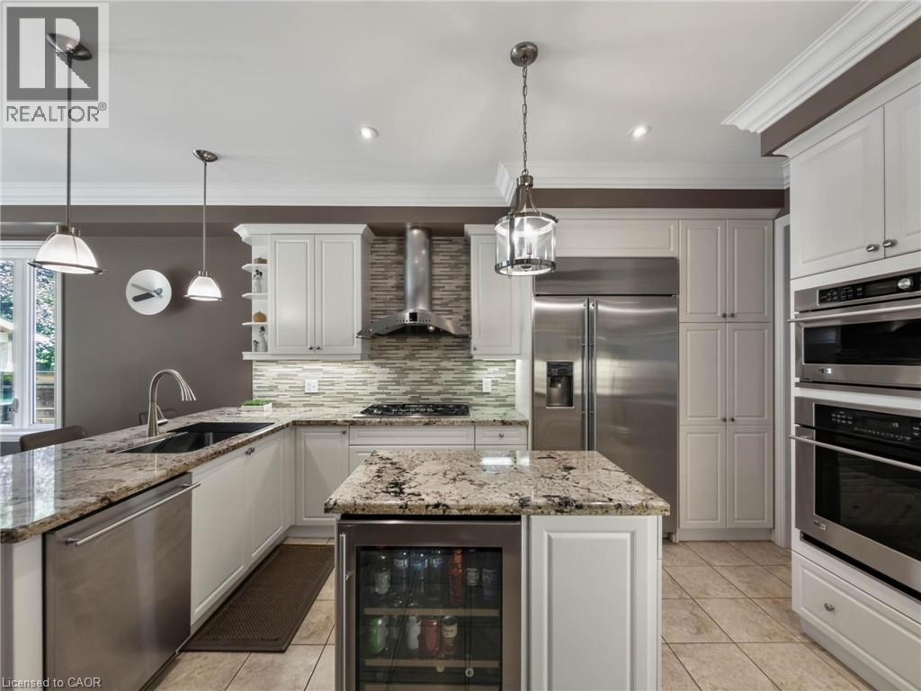 Gourmet kitchen featuring white cabinetry with shaker-style doors, granite countertops, and a large center island with integrated beverage cooler - 80 Sutherland Crescent, Ancaster, ON - Indoor Photo Showing Kitchen With Upgraded Kitchen