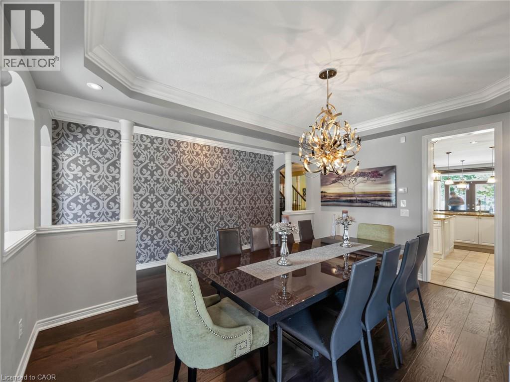 Formal dining area featuring dark wood-finish flooring, a decorative accent wall with patterned wallpaper, and white crown molding - 80 Sutherland Crescent, Ancaster, ON - Indoor Photo Showing Dining Room