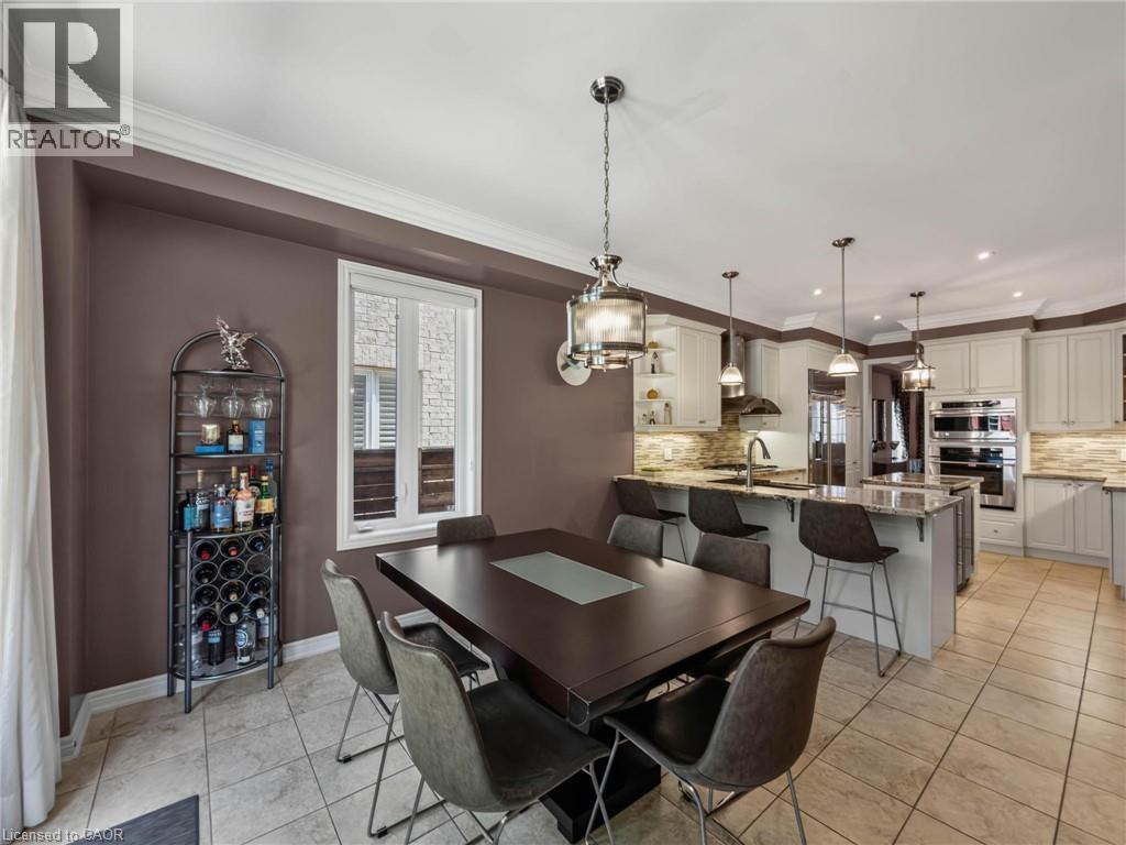 Open-concept dining area featuring a dark wood dining table, overhead pendant lighting, and a window with white trim - 80 Sutherland Crescent, Ancaster, ON - Indoor Photo Showing Dining Room