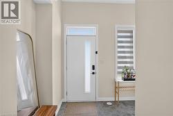 Entryway featuring a solid white door with a vertical glass panel and transom window, dark tile flooring, and light neutral wall paint - 