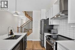 Modern kitchen featuring white shaker cabinetry, stainless steel appliances, a subway tile backsplash, and light countertops - 