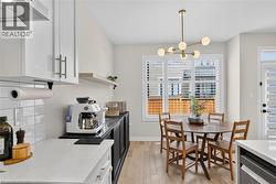 Modern kitchen and dining area featuring white shaker cabinetry with stainless steel hardware, white subway tile backsplash, and white quartz countertops - 