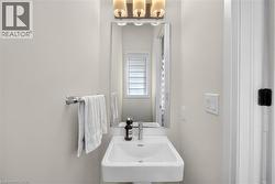 Pedestal sink with a polished chrome faucet, a rectangular mirror, and a three-light vanity fixture - 