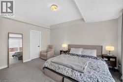 Carpeted bedroom featuring neutral wall tones, a paneled door with black hardware, recessed lighting, and a ceiling-mounted light fixture - 