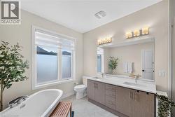 Bathroom featuring a freestanding bathtub, a double vanity with stone countertop, and two vanity light fixtures - 