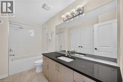 Spa-inspired master bathroom featuring a dual-sink vanity with black countertop, wood-finish cabinetry, and chrome hardware - 