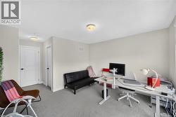 Versatile bonus room featuring neutral carpet flooring, recessed ceiling lighting, two white panel doors for privacy, and ample space configured for home office or recreational use - 