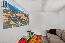 Modern recreation room featuring a large-format wall-mounted display screen, neutral wall finishes, polished concrete flooring, and a contemporary upholstered sofa with accent pillows - 