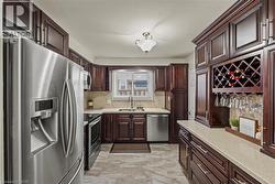 Kitchen featuring dark wood cabinetry, stainless steel appliances, light-toned countertops, a tile backsplash, and a built-in wine rack with stemware storage -