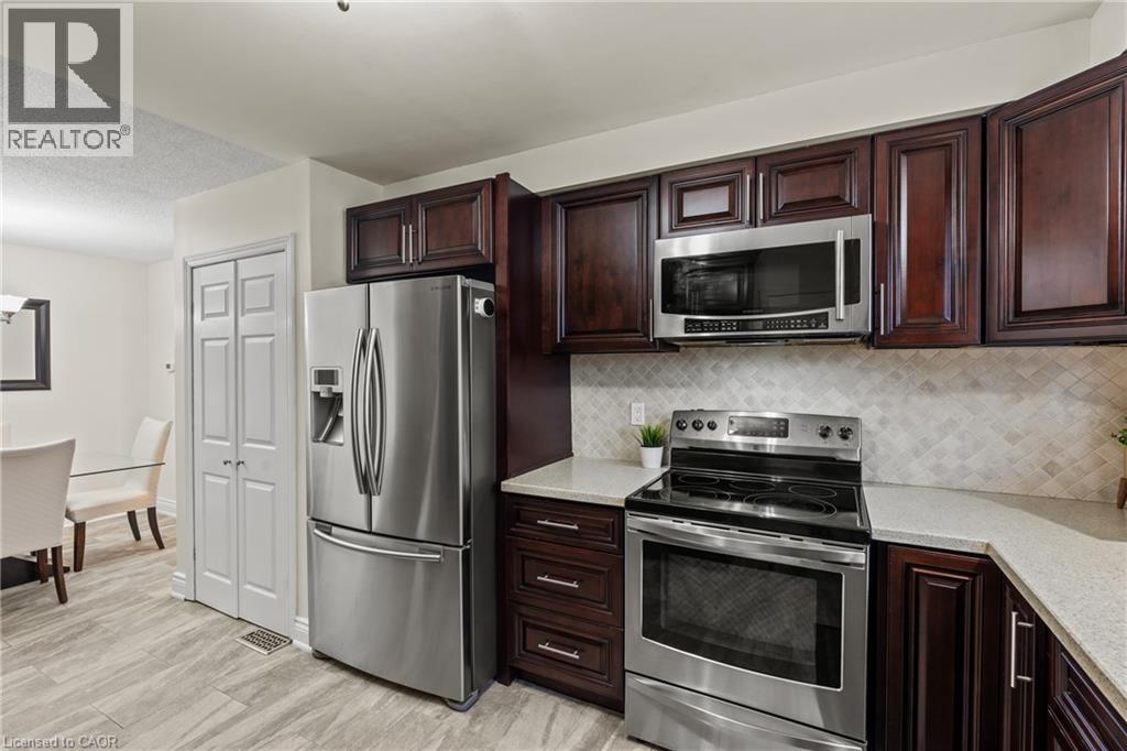 Kitchen featuring rich wood cabinetry, stainless steel appliances, light-toned countertops, and a patterned tile backsplash - 167 Berkindale Drive, Hamilton, ON - Indoor Photo Showing Kitchen