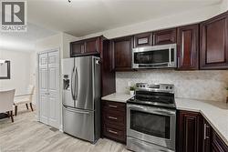 Kitchen featuring rich wood cabinetry, stainless steel appliances, light-toned countertops, and a patterned tile backsplash -