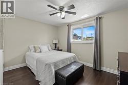 Bedroom featuring dark wood-finish flooring, light neutral wall paint, and white baseboard trim -