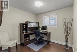 Interior room featuring wood-finish flooring, light neutral-toned walls, and a window with horizontal blinds -