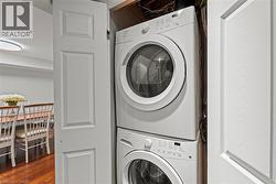 Dedicated laundry closet featuring a stacked white washer and dryer unit -