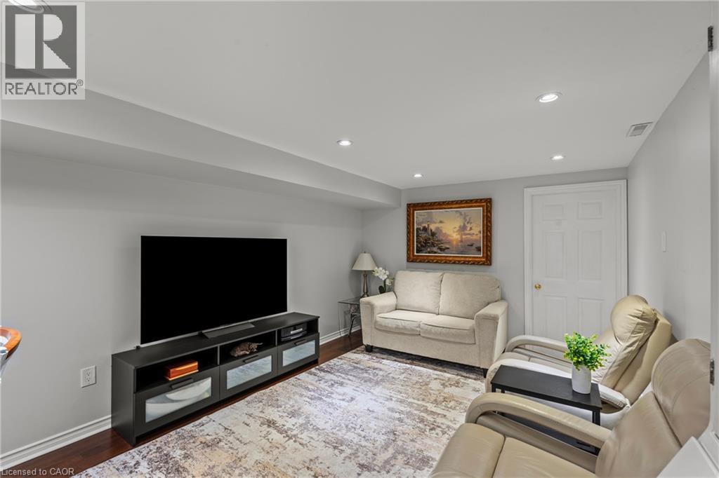 Living space featuring recessed lighting, light gray wall paint, dark wood-finish flooring, white baseboards, and a white interior door with brass hardware - 167 Berkindale Drive, Hamilton, ON - Indoor Photo Showing Living Room
