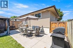 Expansive concrete patio area featuring a privacy fence, a partial grass lawn, and exterior siding -
