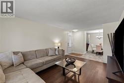 Living area featuring wood-finish flooring, a neutral wall palette, and an open entryway to a dining space -