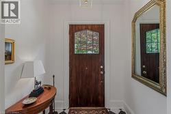 Entryway featuring a dark wood door with leaded glass, framed by white walls and black and white checkerboard flooring - 