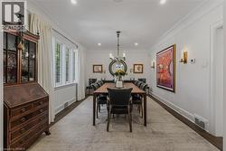 Elegant formal dining room featuring a wood-top table with black upholstered chairs, pendant lighting fixture, and crown molding throughout - 