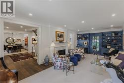 Elegant living room featuring a fireplace with white mantelpiece and surround, recessed ceiling lighting, and hardwood flooring - 