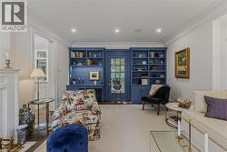 Sophisticated home office and library featuring custom built-in cabinetry with deep blue painted shelving, recessed lighting, and display niches - 