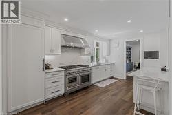 Sophisticated kitchen featuring white shaker-style cabinetry, stainless steel dual-oven range with professional-grade cooktop, marble subway tile backsplash, white quartz countertops, and recessed cei - 