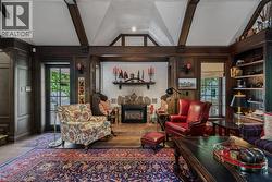 Sophisticated living room showcasing exposed ceiling beams, hardwood flooring, and a gas fireplace with decorative mantel - 