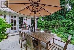 Expansive paver patio with perimeter landscaping and mature trees - 