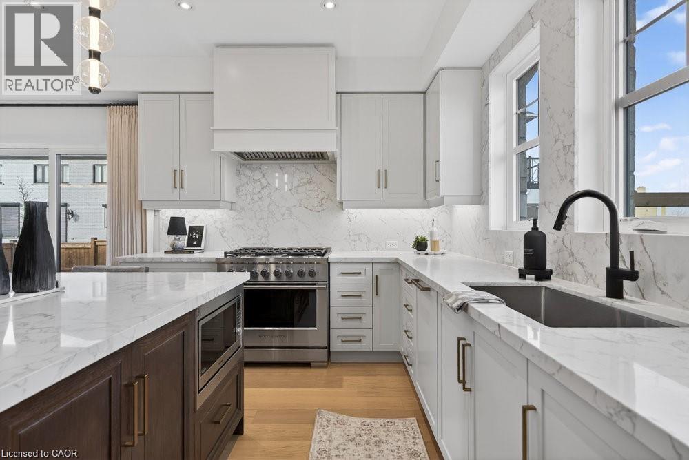 Custom cabinetry, white stone countertops, stainless steel range, and wood-finish flooring - 100 Watershore Drive Unit# 15, Hamilton, ON - Indoor Photo Showing Kitchen With Upgraded Kitchen