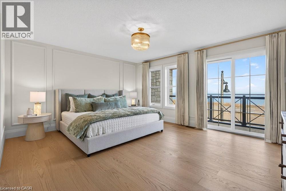 Wood-finish flooring, wall paneling, built-in ceiling light fixture, and sliding glass doors to a balcony - 100 Watershore Drive Unit# 15, Hamilton, ON - Indoor Photo Showing Bedroom