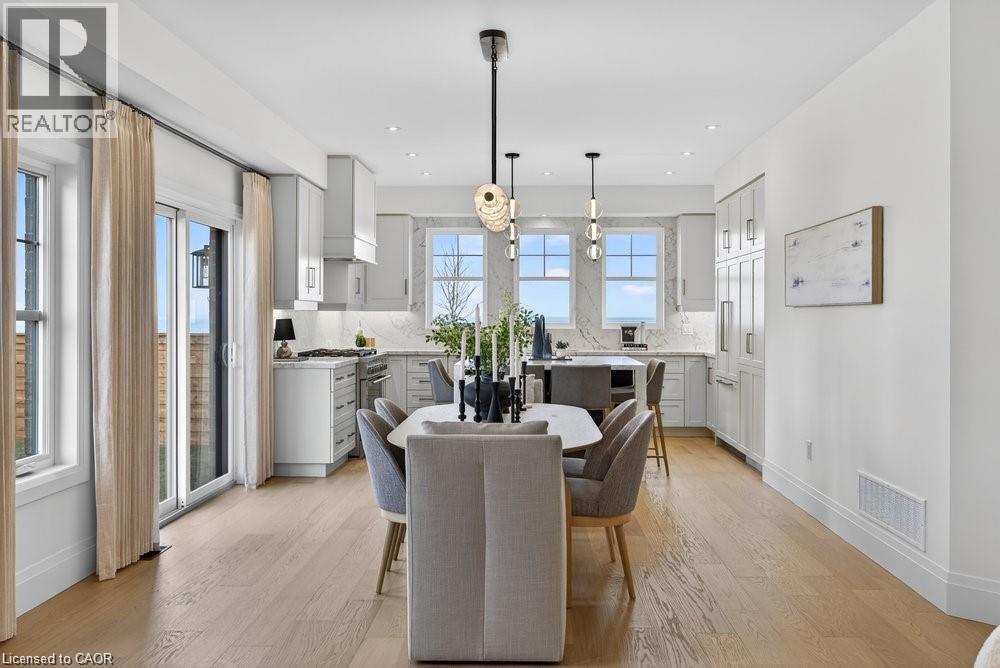 Open-concept living space featuring wood-finish flooring, a modern kitchen with light cabinetry, stainless steel appliances, and a built-in refrigerator - 100 Watershore Drive Unit# 15, Hamilton, ON - Indoor Photo Showing Dining Room