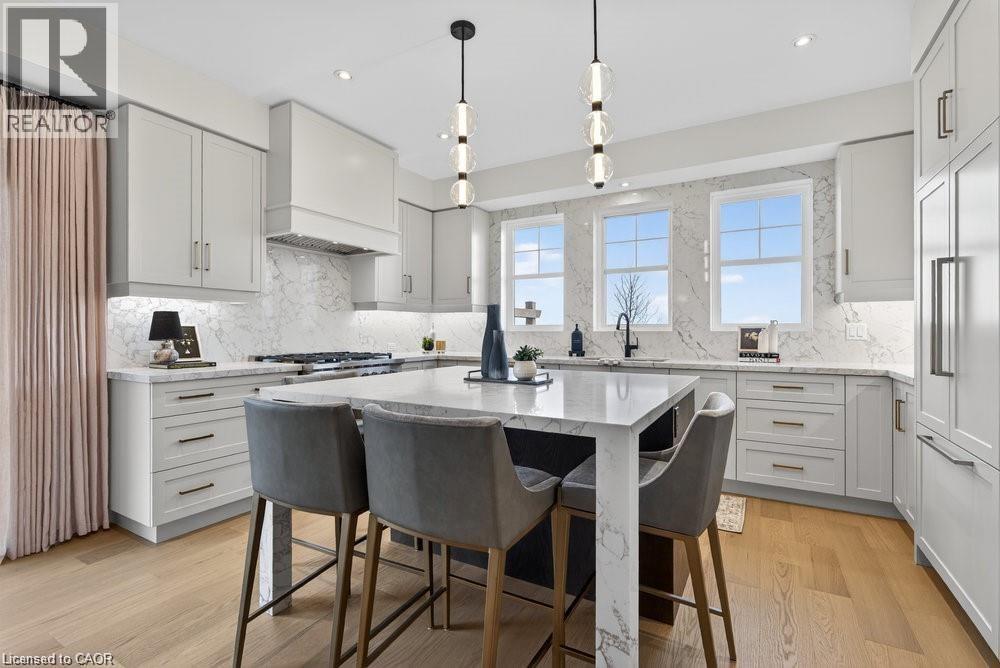 Sophisticated kitchen and dining area featuring custom cabinetry with soft-close drawers, marble-topped island with seating for multiple, professional-grade stainless steel appliances, marble subway t - 100 Watershore Drive Unit# 15, Hamilton, ON - Indoor Photo Showing Kitchen With Upgraded Kitchen